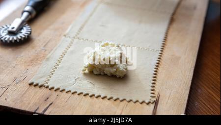Kalitsounia Cretan traditional pies preparation. Homemade dough and stuff with mild cheese and egg, close up view. Stock Photo