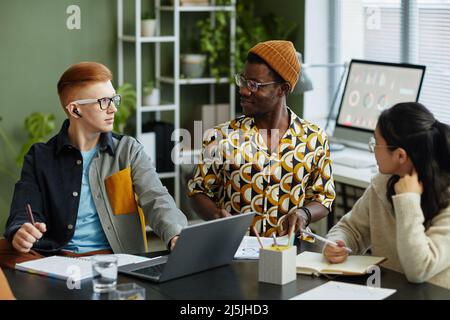 Portrait of young creative team sharing ideas in business meeting all wearing vibrant style Stock Photo