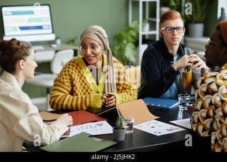 Portrait of creative young woman with team working on project together in business meeting Stock Photo