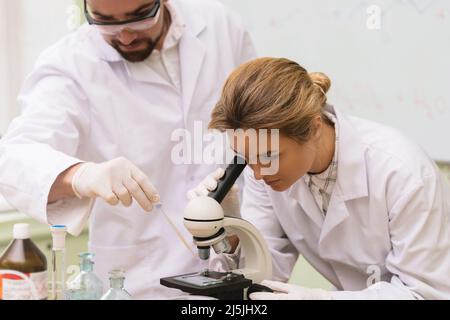 Two scientist colleagues are using microscope during research work in a laboratory Stock Photo