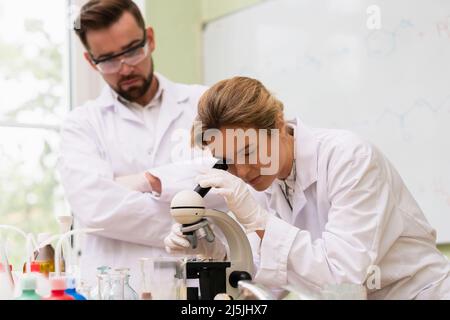 Two scientist colleagues are using microscope during research work in a laboratory Stock Photo