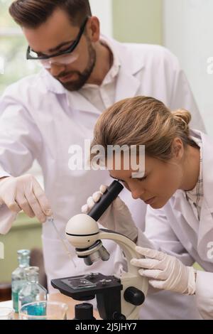 Two scientist colleagues are using microscope during research work in a laboratory Stock Photo