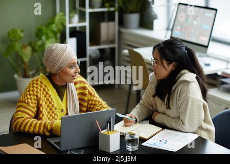Portrait of two creative young women collaborating in business meeting while enjoying work in office Stock Photo