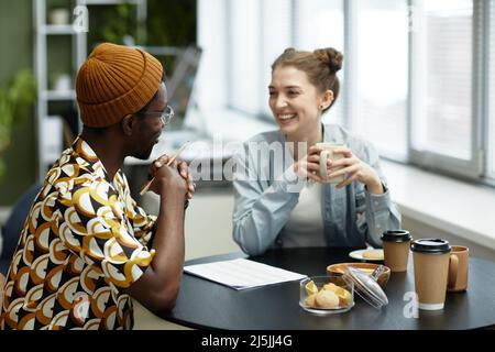 Portrait of two creative young people laughing together while enjoying work on project Stock Photo