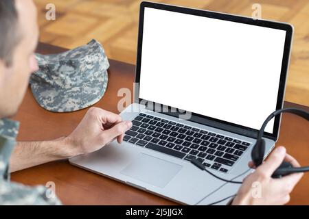 Army. Young soldier working with a laptop computer with blank screen on black background. Stock Photo