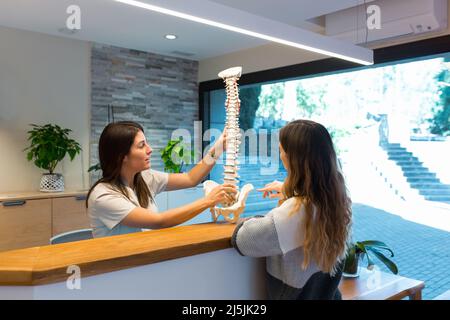 Physiotherapist holding a model of spine and showing and explaining the spinal hernia to patient Stock Photo