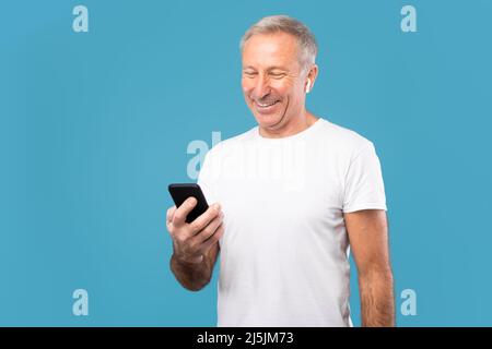 Mature man using his mobile phone wearing wireless earphones Stock Photo
