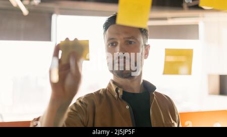 Businessman Sticking Notes On Glass Wall Working Standing In Office Stock Photo