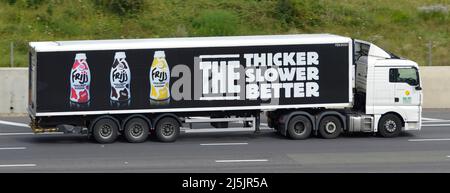 Side view white Dairy Crest hgv lorry truck & long black articulated trailer advertising graphic Muller Frijj milkshake drink bottles UK motorway road Stock Photo