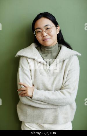 Minimal portrait of Asian young woman wearing comfy knit sweater looking at camera with candid smile Stock Photo