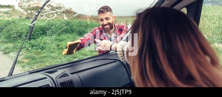 Man cleaning van windshield while woman pointing stain Stock Photo