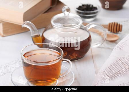 Still life with glass cup of tea and teapot on white wooden table Stock Photo