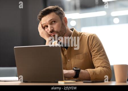 Unhappy Businessman Sitting Near Laptop Thinking Sitting In Office Stock Photo