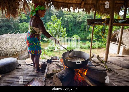 An Embera puru indian woman is frying plantain inside in the Embera puru village, Rio Pequeni, Republic of Panama, Central America. Stock Photo