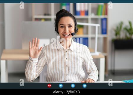 Head shot of cheerful female employee worker waving hand to webcam, greeting colleagues at online meeting, screen view Stock Photo