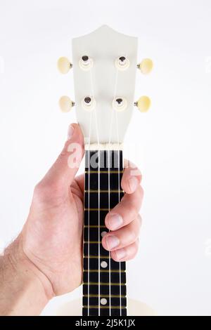 a strings of a beautiful white guitar close-up on a white background ukulele in a male hand Stock Photo
