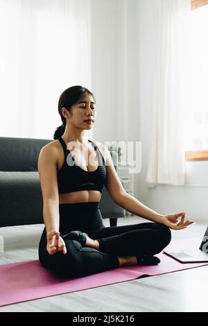 Smiling young girl practicing yoga sitting in lotus pose