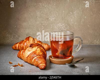 freshly baked croissants and tea cup on grey table Stock Photo