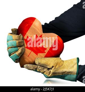 Manual worker with protective work gloves holding a brown wooden heart with the Canadian Flag painted on the surface, isolated on white background. Stock Photo
