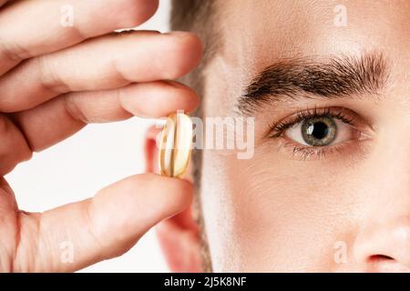 Man holding capsule with a fish or krill oil source of fatty acids such as DHA and EPA Stock Photo