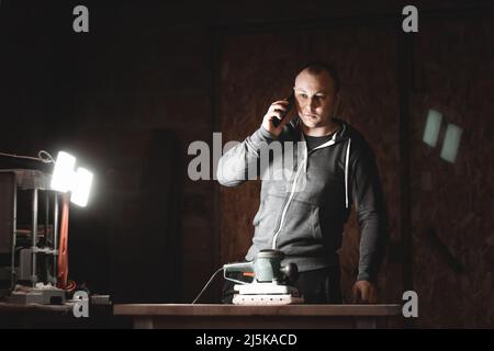 Portrait of a carpenter talking on the phone in a woodworking workshop Stock Photo
