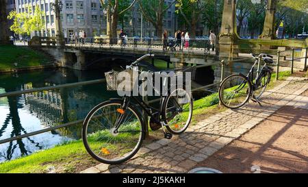 Königsallee is not only a famous shopping boulevard in Düsseldorf, but also has green areas with old trees. Bikes parked at the city canal 'Kö-Graben'. Stock Photo