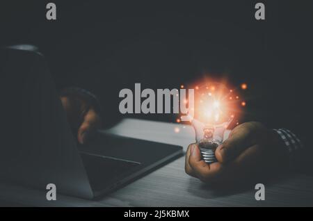 businessman holding a light bulb with a laptop computer.Digital creative design concept technology marketing. Stock Photo