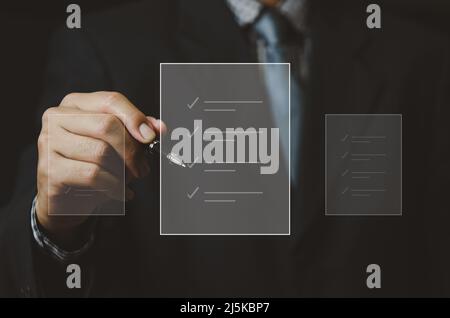 businessman holding pen to check business digital documents on virtual screen. Stock Photo