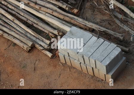 View from a small construction site where the pile of bricks and wooden poles for scaffolding are kept on the ground Stock Photo
