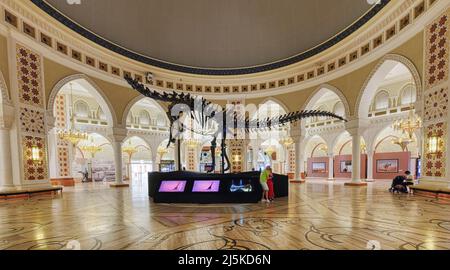 DUBAI, UNITED ARAB EMIRATES - APRIL 7: (EDITORS NOTE: Image is a digital [High Dynamic Range] composite.) A couple gets photo taken in front of the dinosaur skeleton at Dubai Mall on April 7, 2022 in Dubai, United Arab Emirates. The 155 million years old skeleton (called ‘Dubai Dino’) is exhibited at the Souk Dome of Dubai Mall. Stock Photo