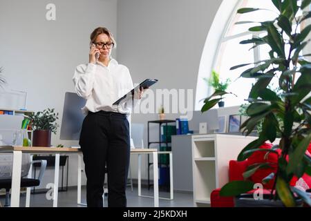 Displeased female office worker talking on the phone Stock Photo
