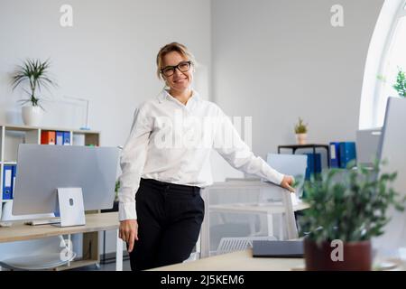 Elegant blonde businesswoman standing in your office Stock Photo