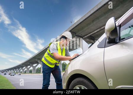 A Civil Engineers use laptop working  inspection project road construction development in front of his car. Stock Photo