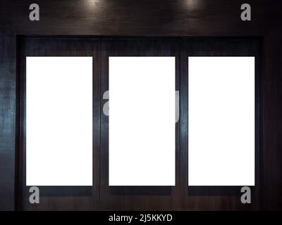 Three mockup vertical rectangle painting frames hanging on dark wood wall background with copy space. Blank white canvas frame with empty space in gal Stock Photo