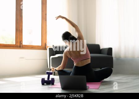 Young attractive woman practicing yoga in online yoga class on mat floors tanding in Full Version of Vasisthasana exercise, Side Plank pose, working Stock Photo