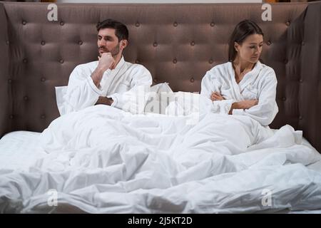 Resentful wife in bed turning away from her husband Stock Photo