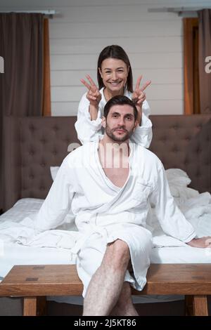 Happy wife giving bunny ears to husband in bed Stock Photo