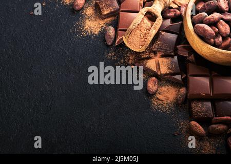 Chocolate . Composition of cocoa powder, grated and bean cocoa bars and pieces of different milk and dark chocolate on black background. Baking Chocol Stock Photo