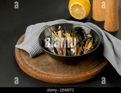 mussels in creamy sauce in a black plate on a black background Stock Photo