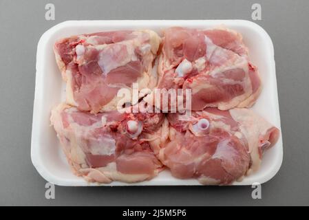Chicken thighs in food plastic tray for sale in supermarket, isolated on gray background, clipping path Stock Photo