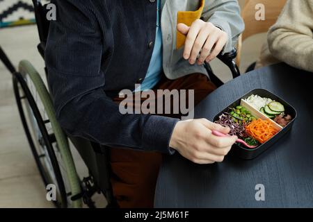 Close up of unrecognizable young man in wheelchair enjoying healthy vegan lunch in office, copy space Stock Photo