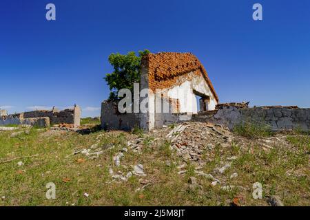 A brick one-story residential old building destroyed by an explosion against a blue sky. Stock Photo