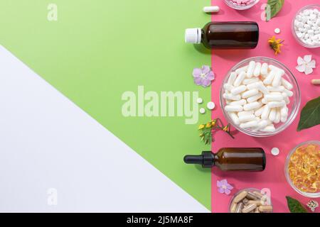 Flat lay composition of various vitamin capsules and dietary supplements on green,pink and white background with copy space. Foodstuffs concept. Stock Photo