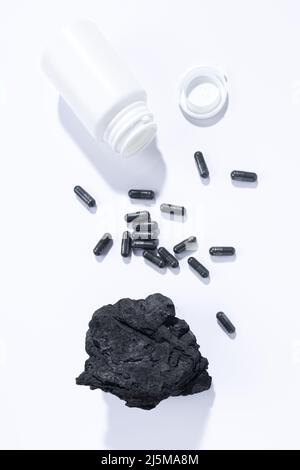 Flat lay composition of vegetable carbon capsules on white background. Vertical format. Dietary supplements concept. Stock Photo