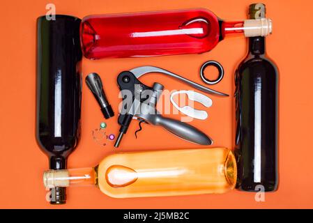 Several bottles of wine, red, white and rosé, placed horizontally, crossed with each other, with a corkscrew and various utensils to use when opening Stock Photo