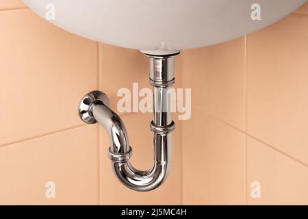 Bathroom beige interior with sink and metal pipe for draining water Stock Photo