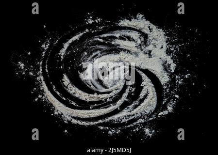 Black background sprinkled with flour, smeared flour, table for cooking, rolling dough. Preparing for baking, top view on a black background or table. Stock Photo