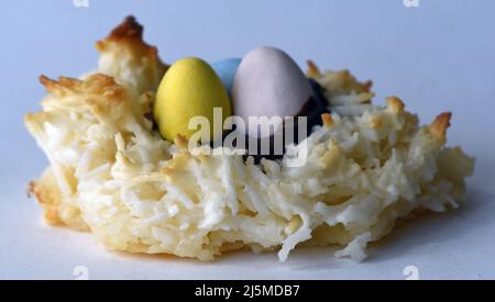 A vanilla coconut macaroon shaped like a bird nest and filled with chocolate and candy coated chocolate eggs. Stock Photo