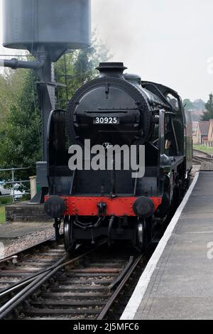 Cheltenham 30925 Schools Class steam locomotive passing a water tower and pulling into Alton train station. Heritage Watercress Line. Hampshire, UK Stock Photo