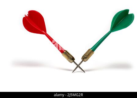 Close up of two plastic darts in red and green color crossed in the area of the tips with pointed metal tip on white background Stock Photo